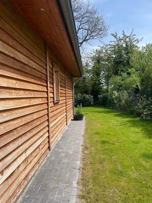 A wooden building with a brick pathway leading to a grassy yard.