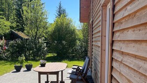 A wooden cabin with a patio, outdoor seating, and a view of the surrounding forest. - Holiday Home 'Strand Haus' with Private Terrace, Private Garden and Wi-Fi (Elsfleth)