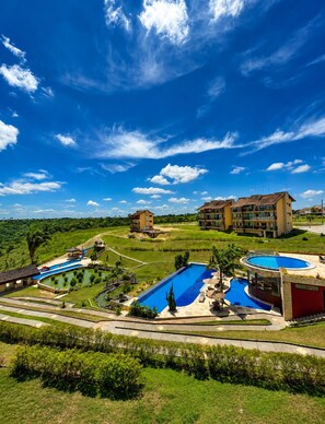 Ein Resort mit mehreren Schwimmbecken, einem Golfplatz und einem großen Gebäude mit Balkonen.