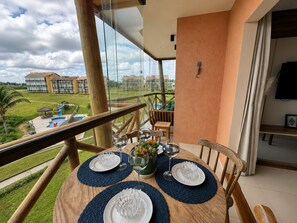 Ein Balkon mit einem Esstisch, der auf einen Pool und die Gebäude des Resorts blickt.