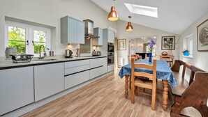 A modern kitchen with a central island, built-in cabinets, and pendant lighting. - Finest Retreats | The Pottage (Oakley)