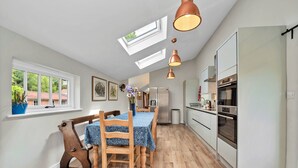 A modern kitchen with a dining area, skylights, and a view of the outside. - Finest Retreats | The Pottage (Oakley)