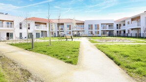Un ensemble résidentiel composé de plusieurs immeubles à deux étages, d’un chemin central et de petits arbres.