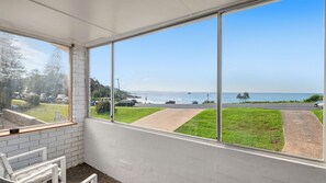 A room with a large window overlooking a road and a body of water. - The Beach House Port Macquarie (Port Macquarie)