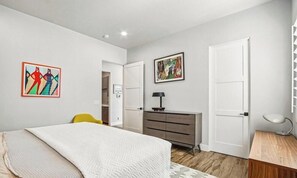 Ein Schlafzimmer mit einem Bett, einem Schminktisch, einem Schreibtisch und zwei Türen.