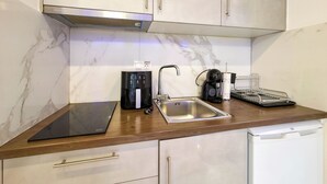 A kitchen with a modern design, featuring a stainless steel sink, a coffee maker, and a black countertop. - 3 - ILEKTRA Suite by SDR (Paralia)