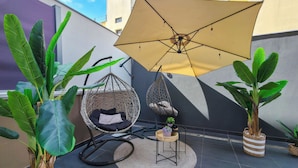 A patio with a hanging chair, a round table, and potted plants. - 3 - ILEKTRA Suite by SDR (Paralia)