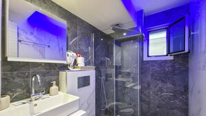 A modern bathroom with a marble sink, a toilet, a shower enclosure, and a glass shower door. - 3 - ILEKTRA Suite by SDR (Paralia)