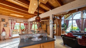 Interior de una cabaña de madera con una isla de cocina, comedor y un sofá.