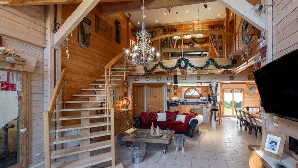 Un interior de madera con una escalera, una sala de estar con sofá y mesa de centro, y un área de cocina.