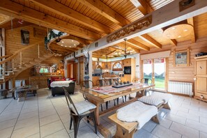 A wooden interior with a dining table, benches, and a staircase.