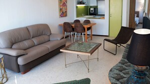 Uma sala de estar com sofá, mesa de centro, mesa de jantar com cadeiras e abajur.