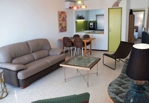 A living room with a sofa, a coffee table, a dining table with chairs, and a lamp.