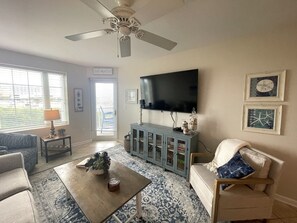 Un salon équipé d’un ventilateur de plafond, d’un téléviseur, d’un meuble et d’un canapé.