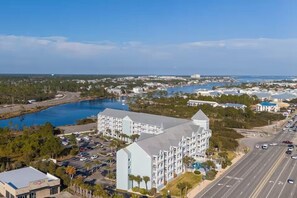 A coastal hotel with a large pool, multiple buildings, and a road leading to the beach. - Grand Caribbean 214 • Fully Renovated • Walk to Beach• Sleeps 6 (Orange Beach)