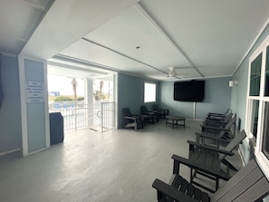 A balcony with a pool view, a ceiling fan, and a sign prohibiting smoking or vaping. - Grand Caribbean 214 • Fully Renovated • Walk to Beach• Sleeps 6 (Orange Beach)