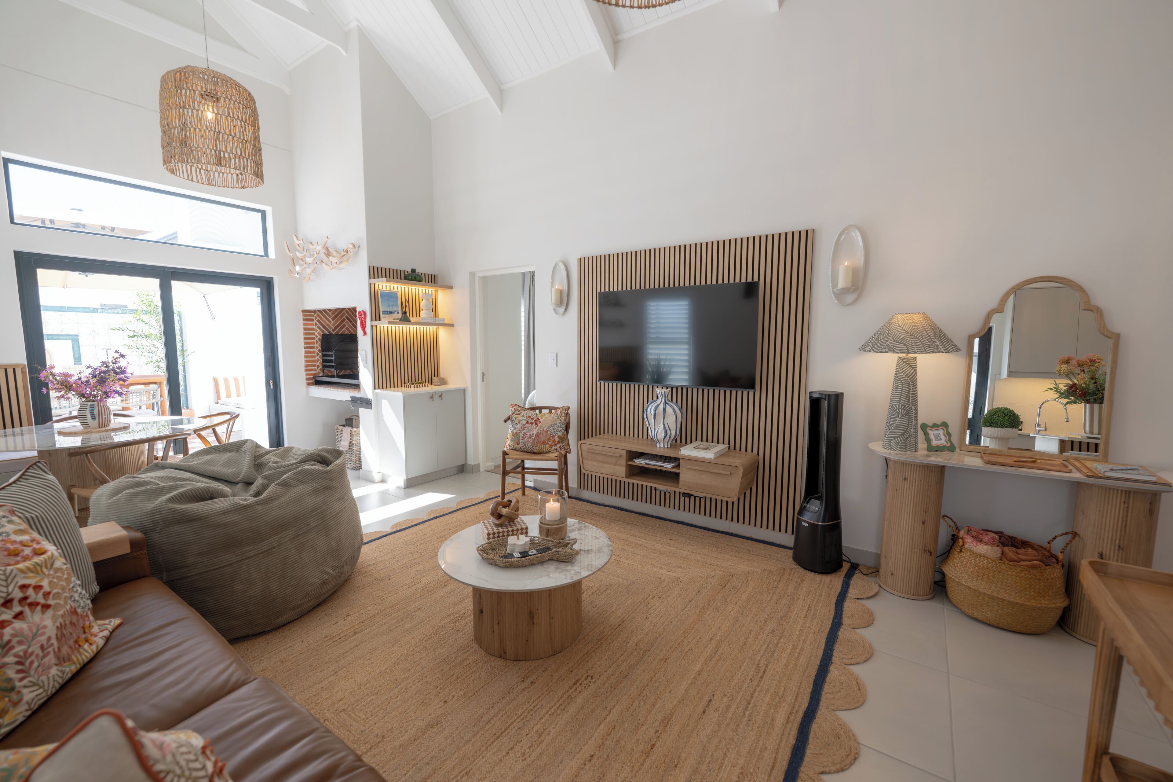 A modern living room with a sofa, bean bag, coffee table, TV, and a fireplace.