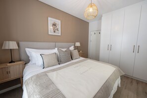 A bedroom with a bed, nightstands, a wardrobe, a hanging light fixture, and a framed picture on the wall. - Sout Huijs Langebaan - A little slice of West Coast Heaven with Hot Tub (Langebaan)