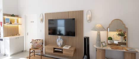 Una sala de estar moderna con un televisor, un panel de pared de madera, una lámpara, un espejo y una pequeña mesa con objetos decorativos.