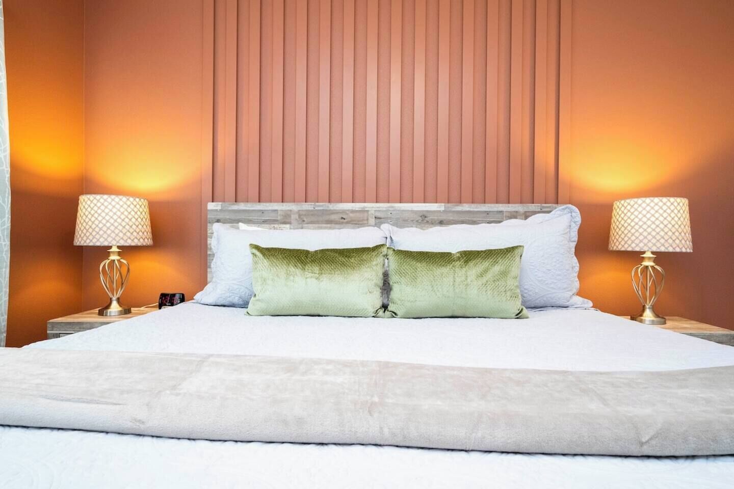 A hotel room with a large bed, two bedside lamps, and a wooden headboard.