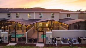 A modern building with a glass-enclosed pool area, outdoor seating, and air conditioning units. - Water View & Beachside Mickey NEAR Disney 2637 (Kissimmee)