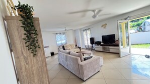 Sala de estar com sofá, TV e ventilador de teto.