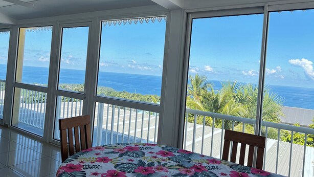 Uma varanda com vista para o oceano, uma mesa com toalha de mesa florida e uma cadeira.