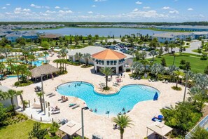 Un resort con una grande piscina centrale, diversi edifici e un lago sullo sfondo.