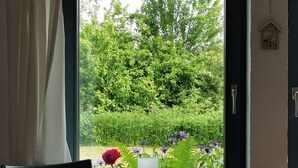A window with a view of a garden, a chair, a table, and a candle. - Simply charming, natural, and beautiful—just 600 meters from the sea! Angeln Courtyard (Nieby)