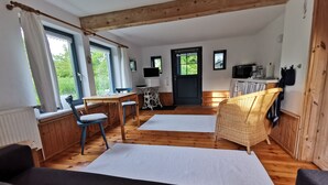 A cozy room with a wooden floor, a bed, a dining table with chairs, a TV, and a kitchen area. - Simply charming, natural, and beautiful—just 600 meters from the sea! Angeln Courtyard (Nieby)