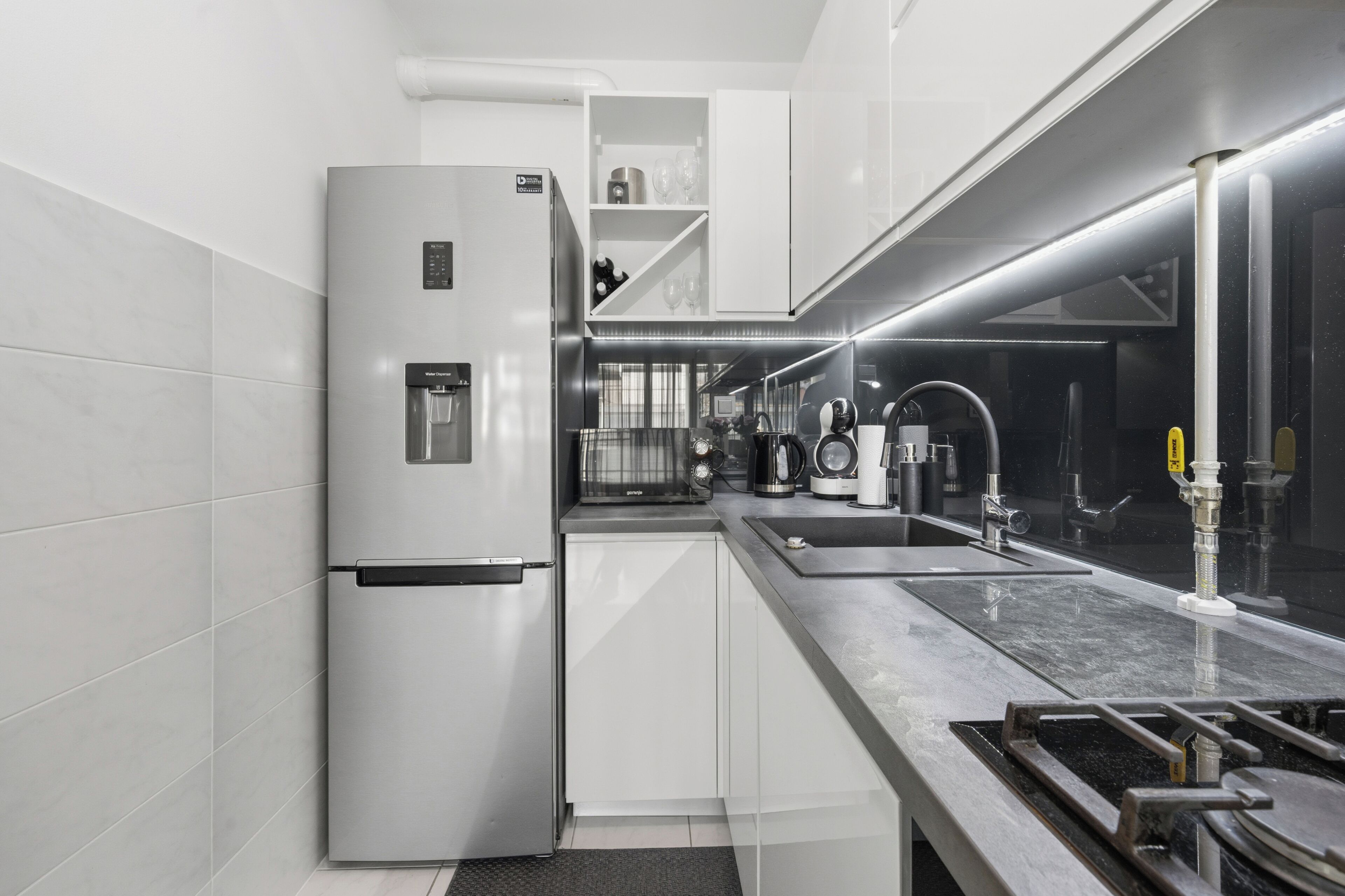 A modern kitchen with a built-in refrigerator, stainless steel appliances, and a long countertop.