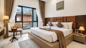 Una camera d'albergo moderna con un letto grande, una sedia, un tavolino e vista sulla città.