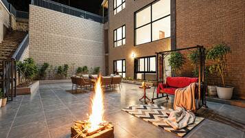 Un patio con un pozo de fuego, mobiliario exterior y una escalera que lleva a un nivel superior.