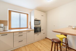 A compact kitchen with a window, a microwave, an oven, and a wooden counter.