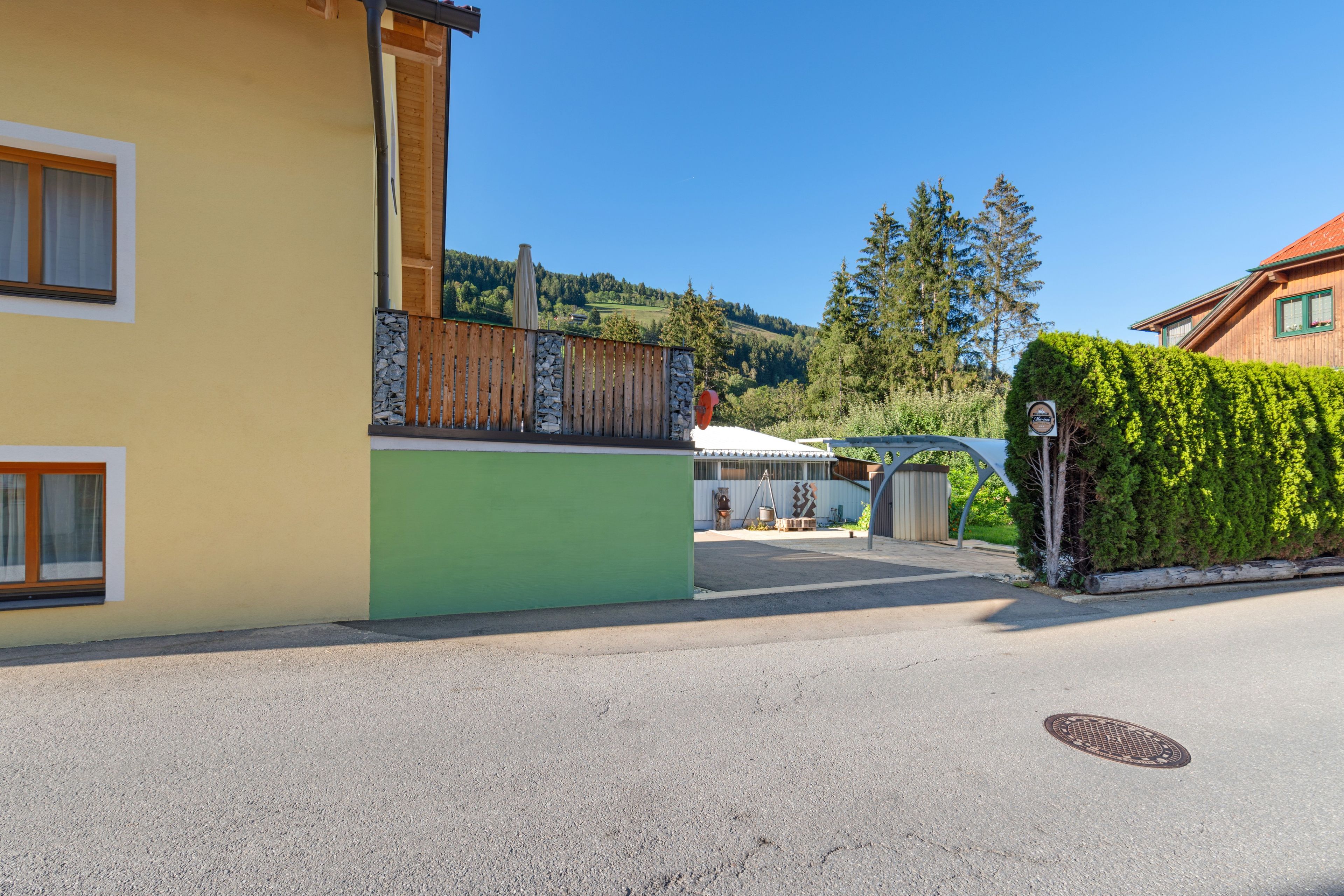 Une vue de rue avec un bâtiment jaune, un mur vert et un ciel bleu clair.