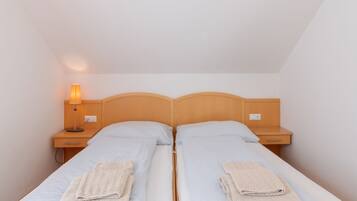 A twin room with two beds, a nightstand with a lamp, and a drawer.