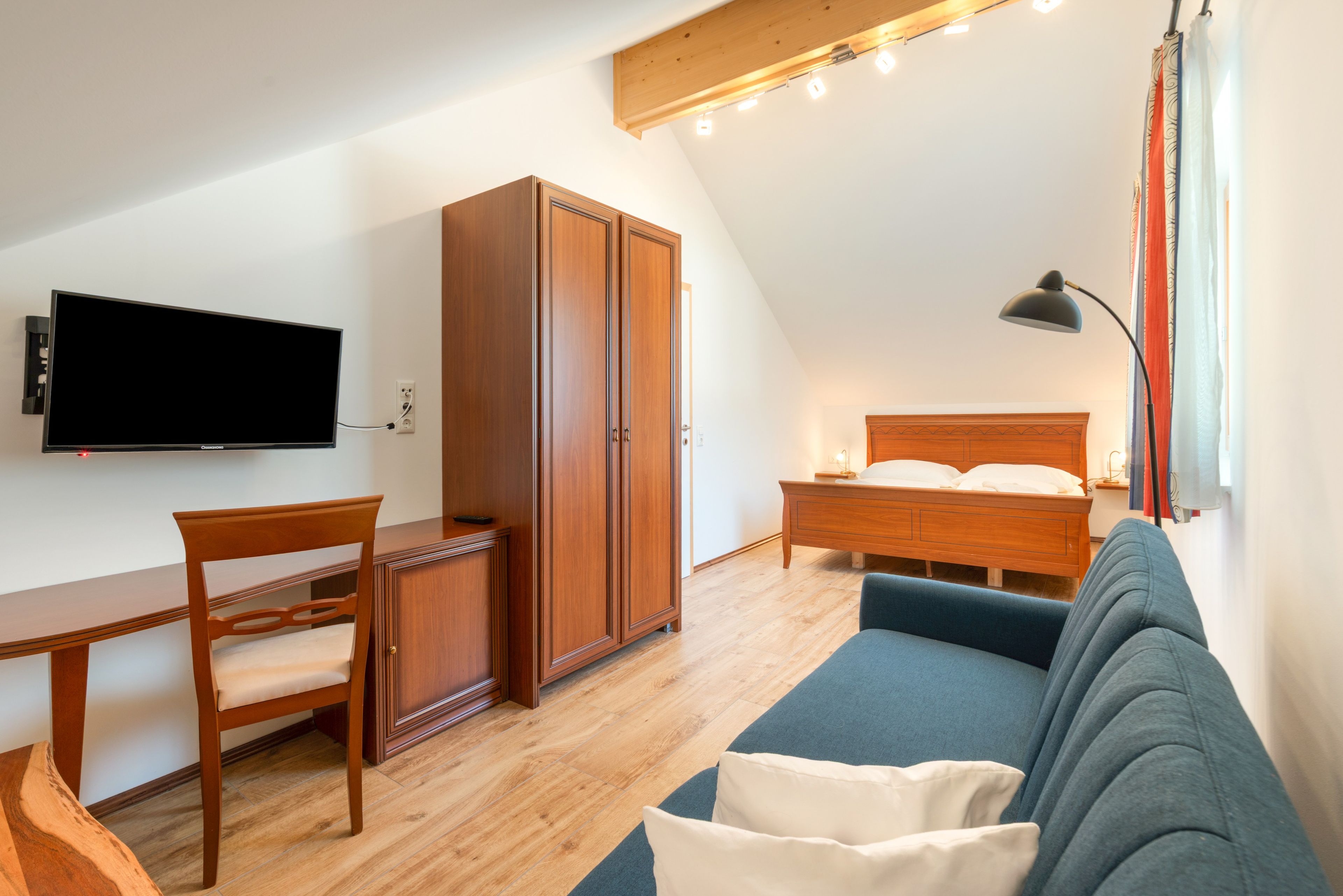 Ein Zimmer mit einem Bett, einem Schreibtisch, einem Fernseher und einem Sofa.