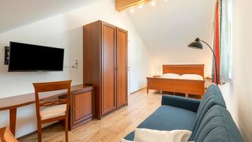 Ein Zimmer mit einem Bett, einem Schreibtisch, einem Fernseher und einem Sofa.