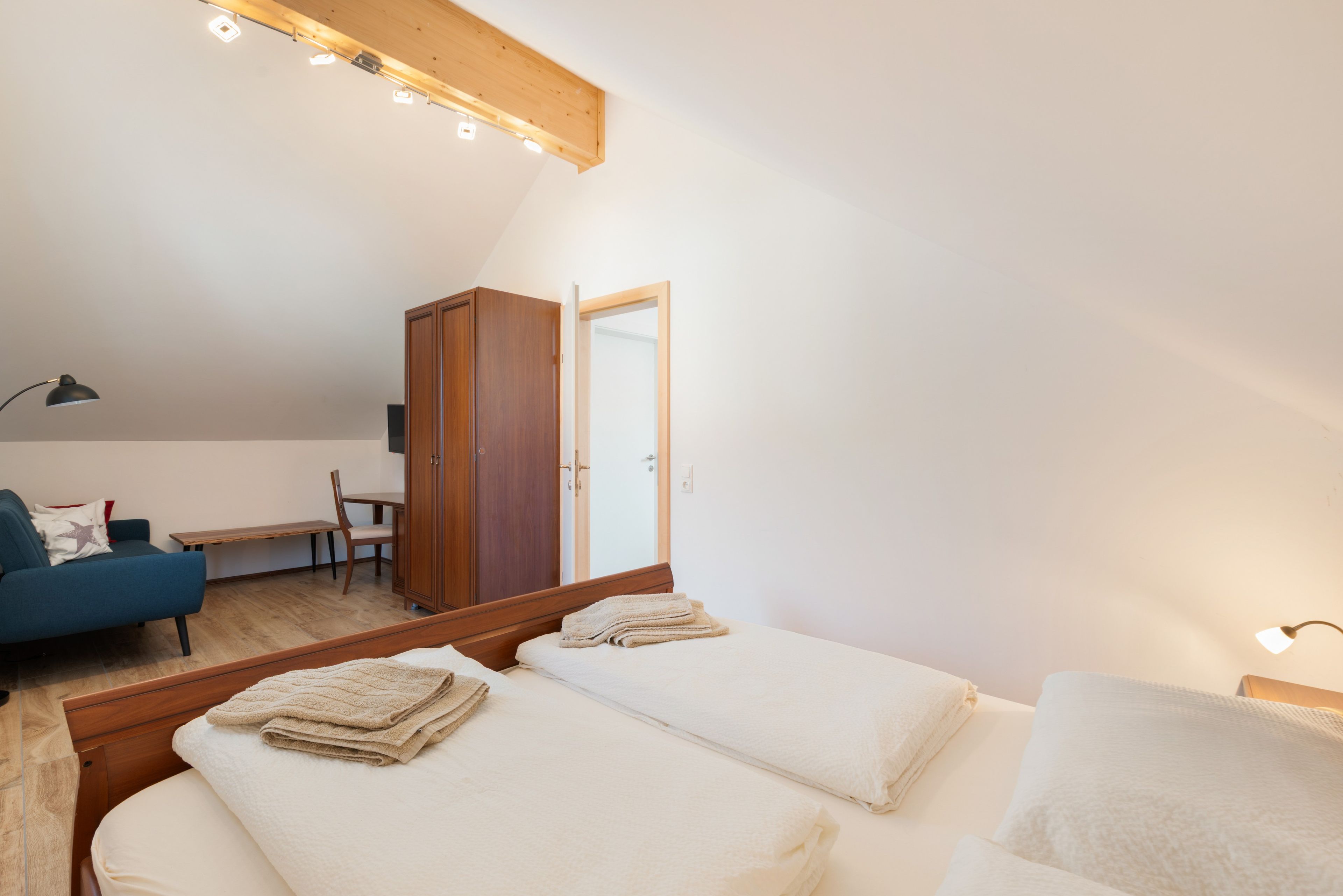 Une chambre avec deux lits, une armoire en bois, un bureau et une chaise.