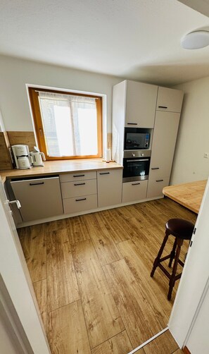 Una cocina compacta con ventana, electrodomésticos integrados y suelo de madera.