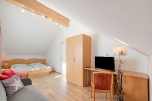 A modern, well-lit room with a bed, a desk, a chair, and a television. - Holiday Home 'Ma-inz.eu' with Mountain View, Private Terrace & Wi-Fi (Steindorf)