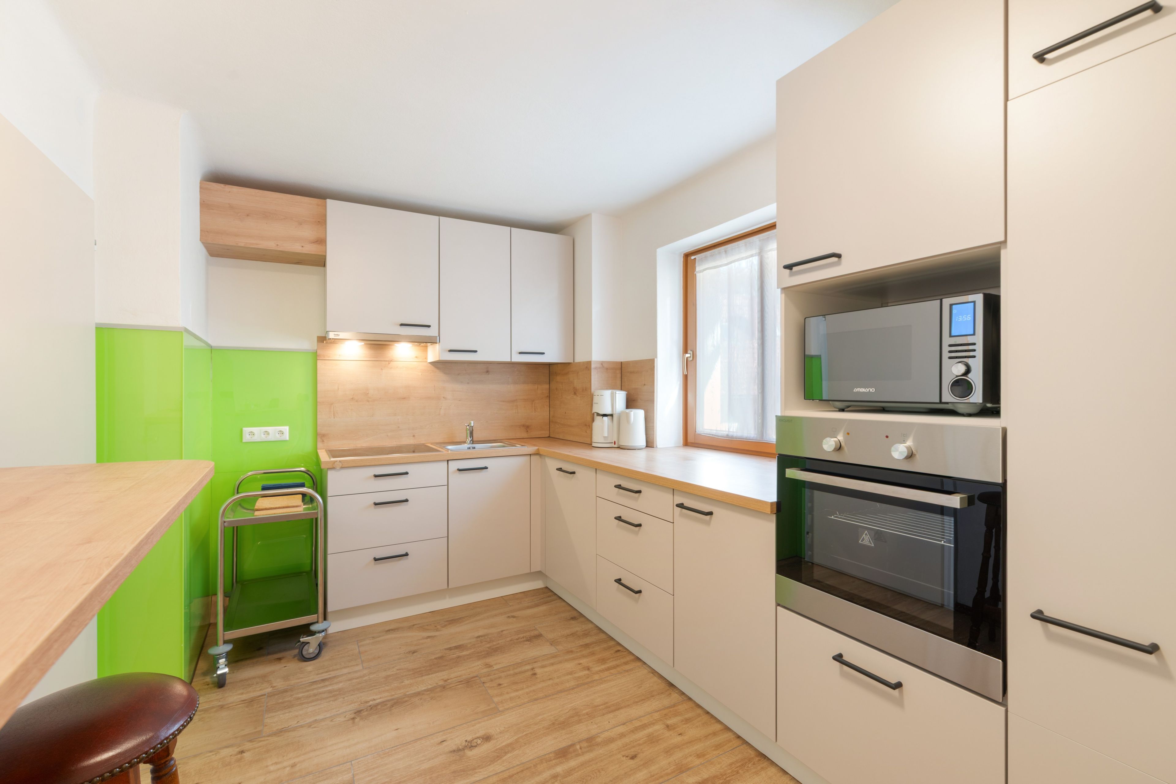 Eine kleine Küche mit Mikrowelle, Backofen und einer grünen Wand.