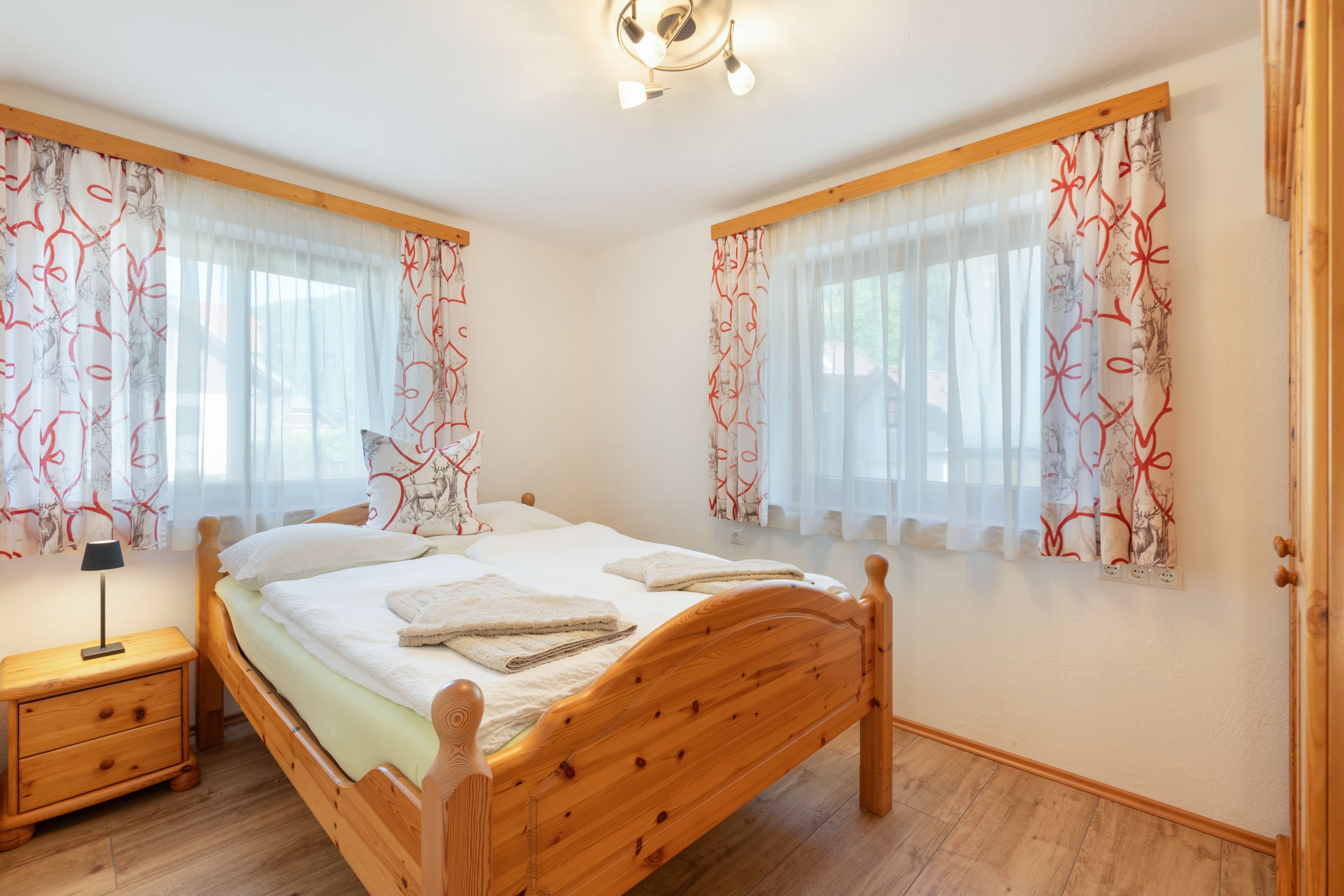 Un dormitorio con una cama de madera, dos mesitas de noche y una lámpara de techo.