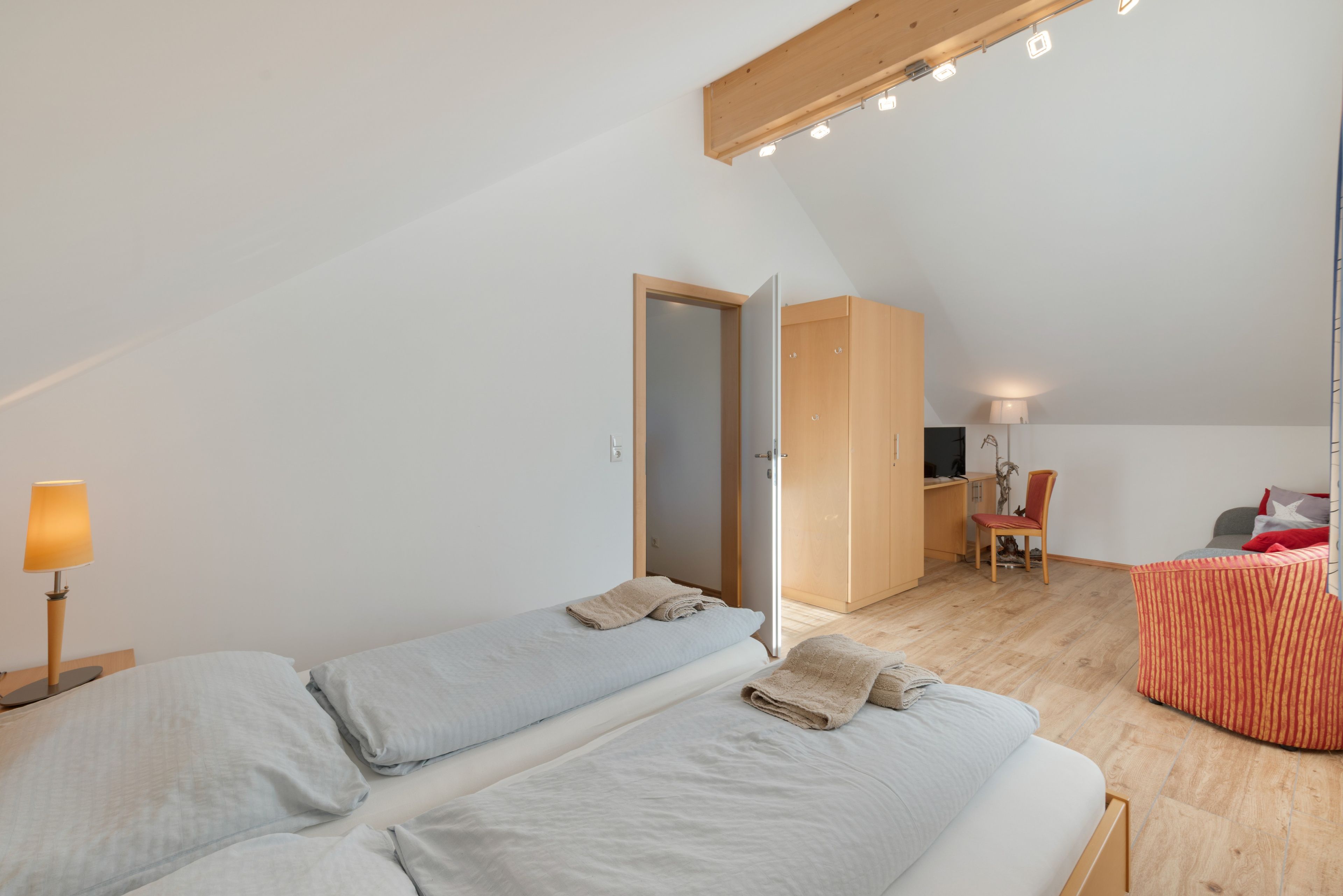 Una habitación con dos camas, un escritorio, una silla y una lámpara.