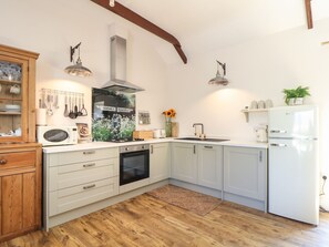 Eine Küche mit weißen Schränken, einem eingebauten Backofen, einer Mikrowelle, einem Spülbecken und einem Kühlschrank.