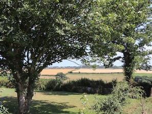 A rural landscape with trees, open fields, and a distant view of a town. - The Forge (Falmouth)