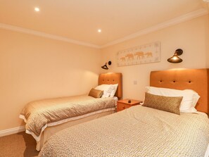 Ein Hotelzimmer mit zwei Betten, einem Nachttisch, einer Wanduhr und einem gerahmten Bild.