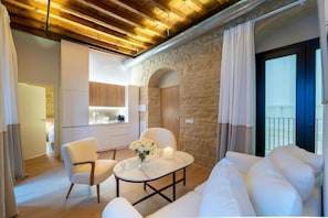 A modern interior with a stone wall, a dining area with a table and chairs, and a balcony with curtains.