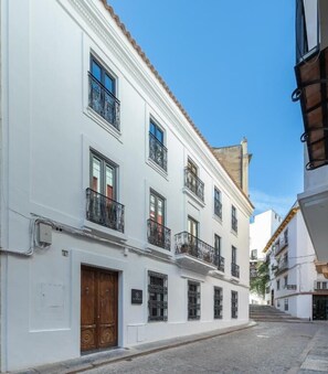 A white building with balconies, a wooden door, and a cobblestone street.