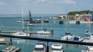 A marina with various boats docked, a flag, and buildings in the background. - Saltwater Apartment Modern 2-bed Waterfront Cowes (Cowes)